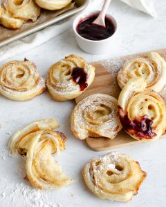 A spread of puff pastry rolls with jam and powdered sugar