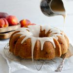 Glaze being poured over peach pound cake