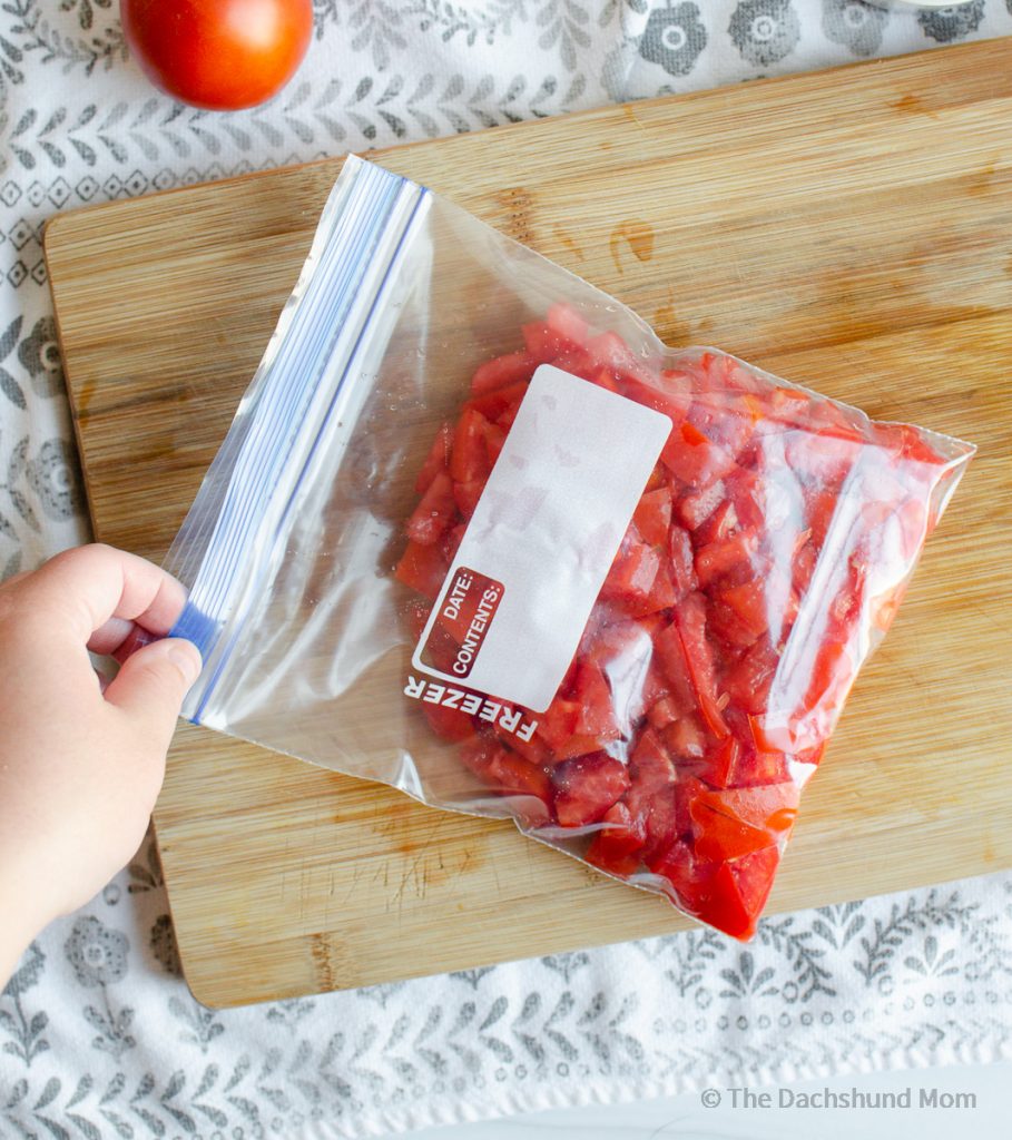 Placing diced tomatoes in a freezer safe bag