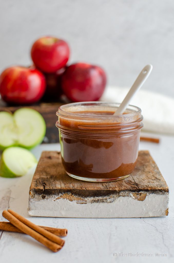 Homemade slow cooker apple butter with fresh apples nearby