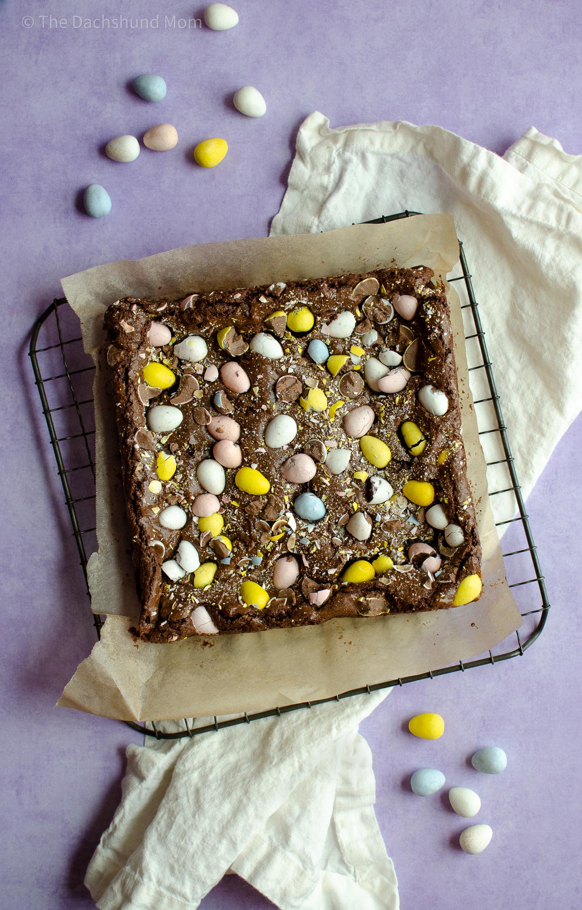 Brownies topped with mini eggs cooling on a rack.